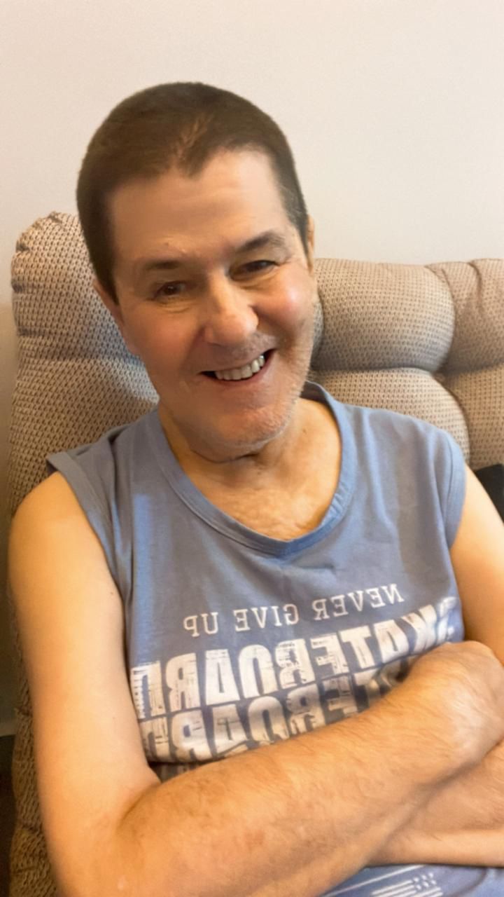 Senhor Celso Garcia sorrindo sentado em poltrona, vestindo camiseta regata